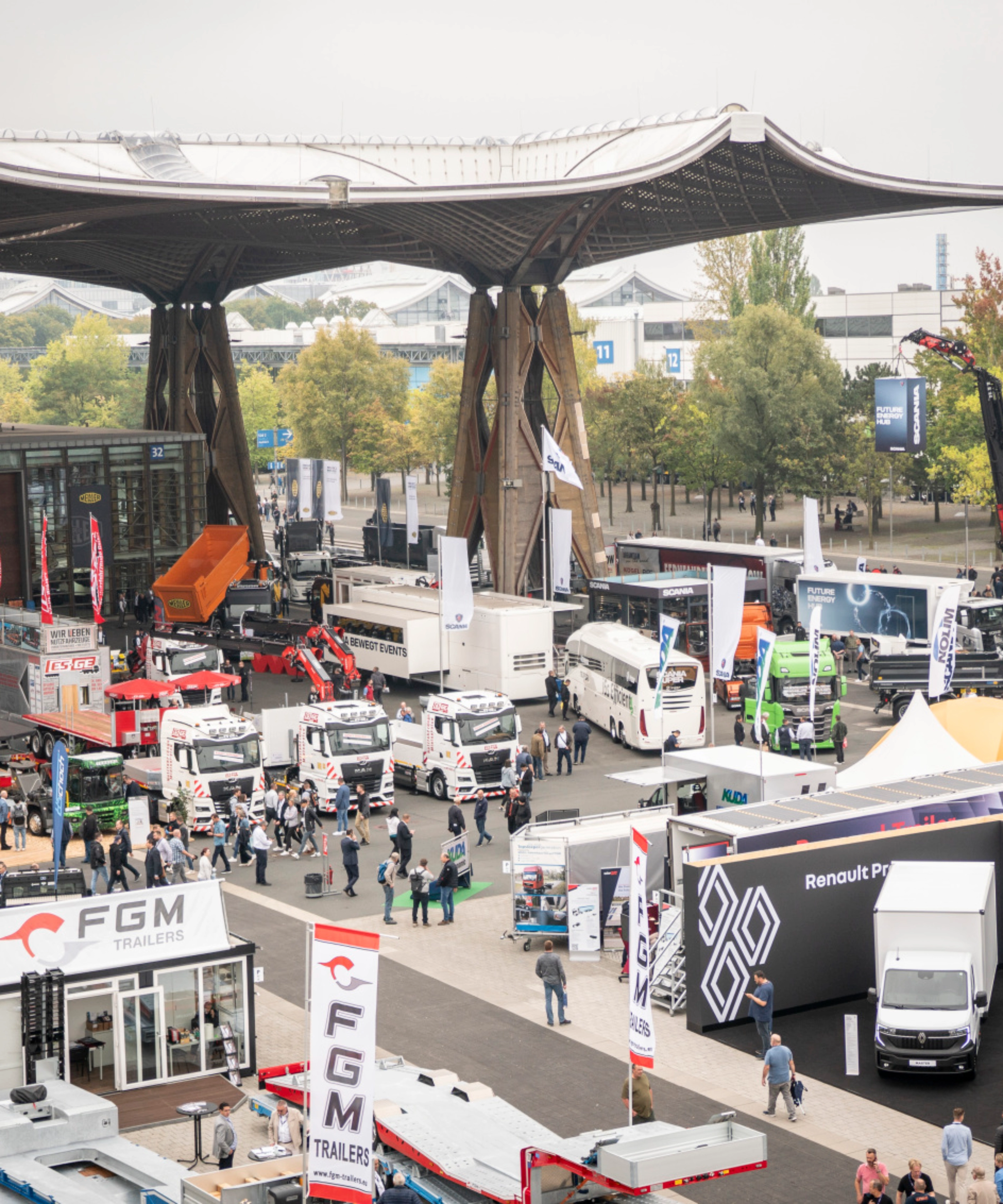 Man presenting vehicle technology on a lit-up stage at a trade fair with audience watching.