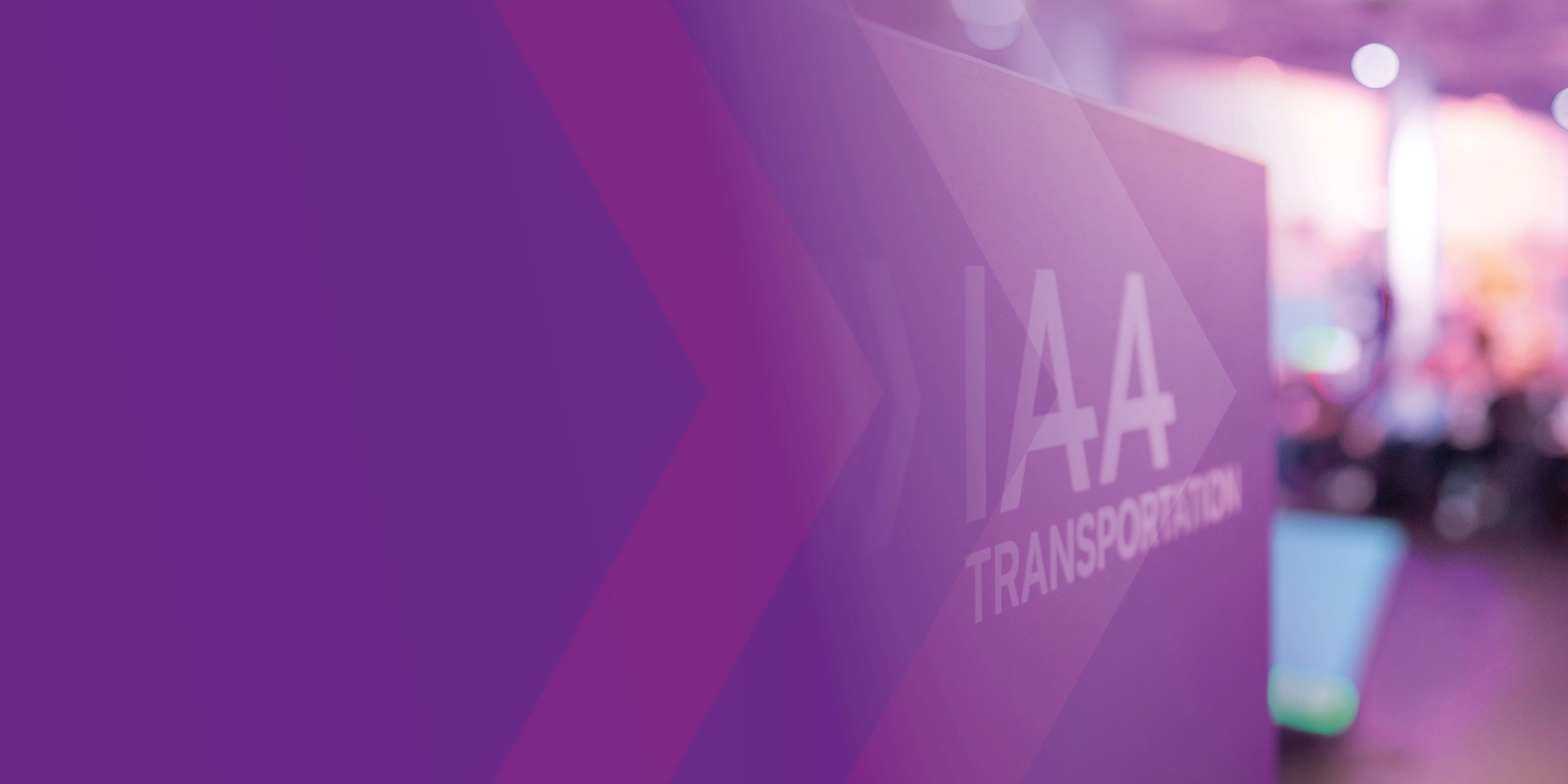 Sign with the text "IAA TRANSPORTATION" at a trade fair, purple design in the foreground.