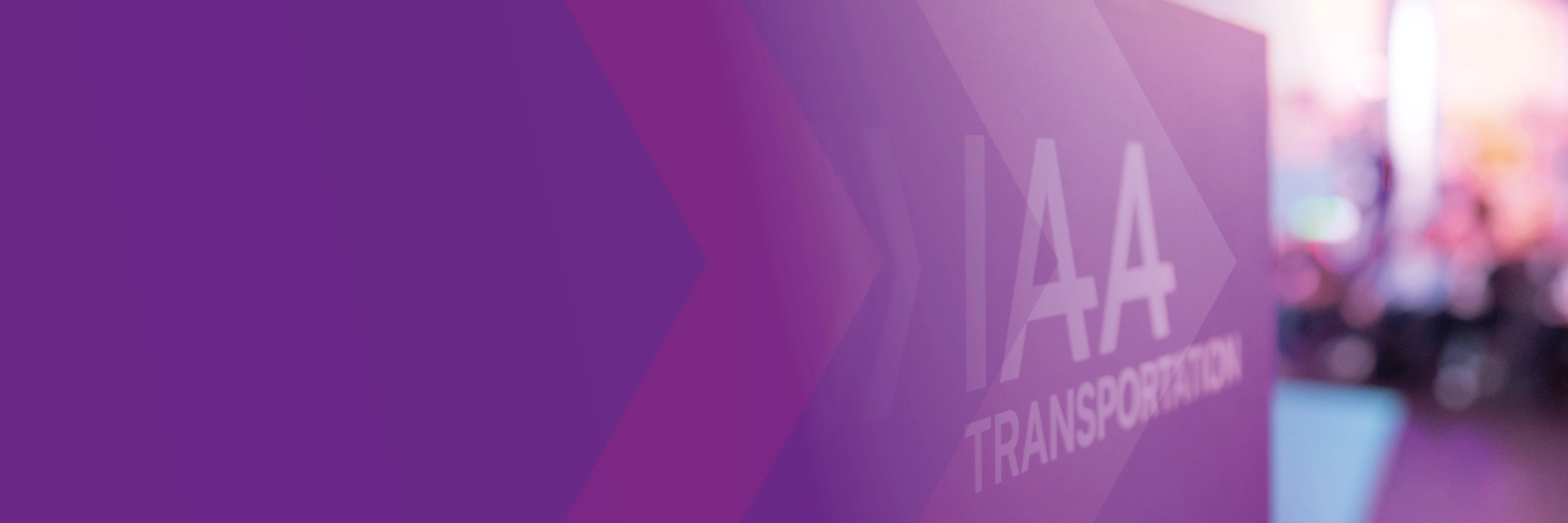 Sign with the text "IAA TRANSPORTATION" at a trade fair, purple design in the foreground.