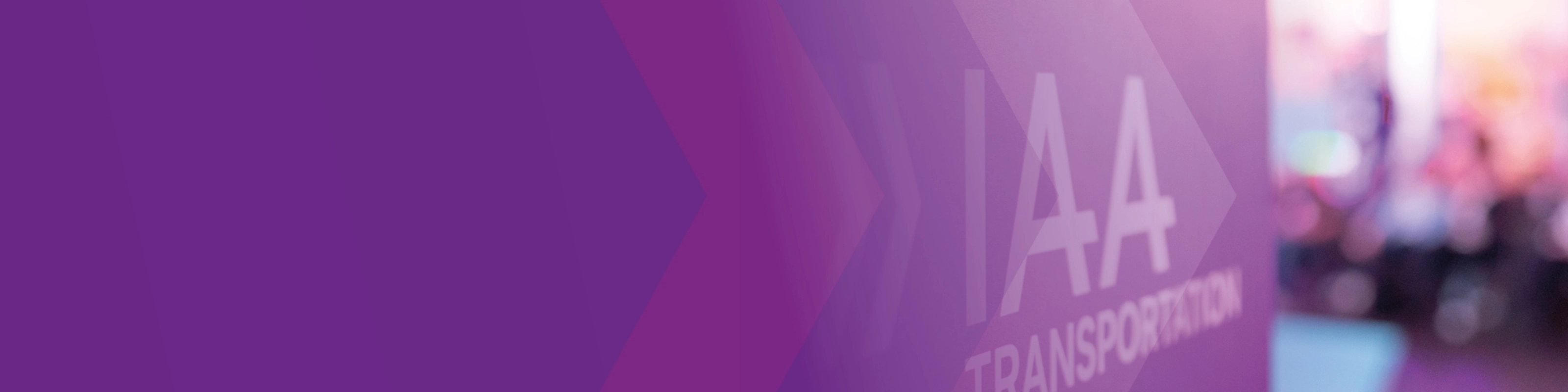 Sign with the text "IAA TRANSPORTATION" at a trade fair, purple design in the foreground.