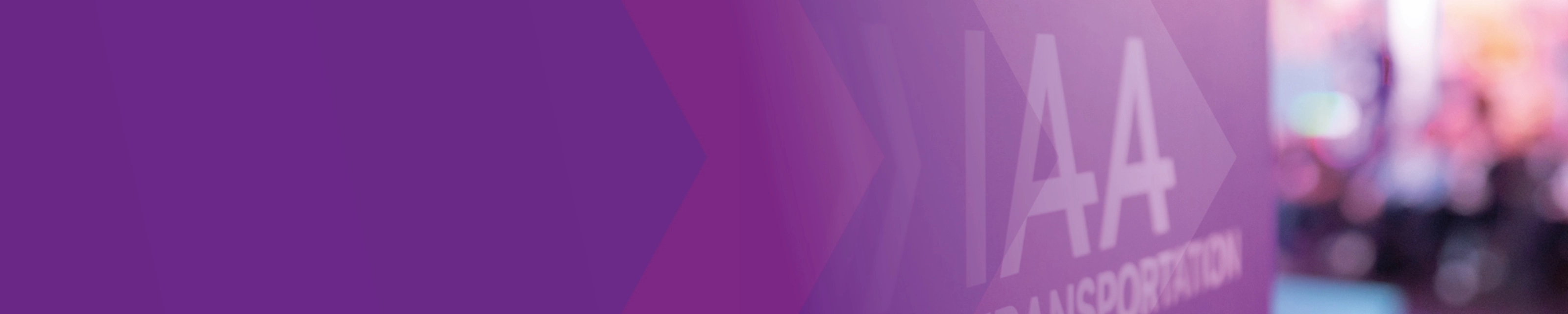 Sign with the text "IAA TRANSPORTATION" at a trade fair, purple design in the foreground.