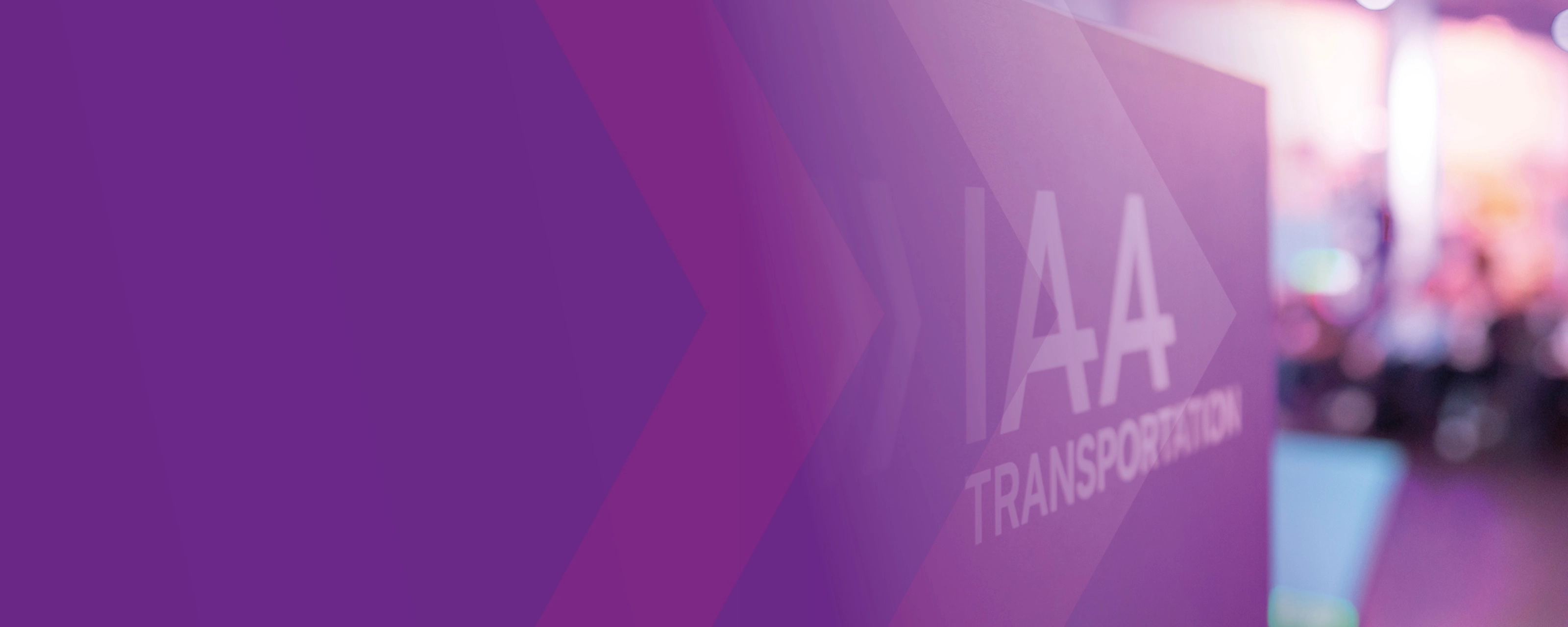 Sign with the text "IAA TRANSPORTATION" at a trade fair, purple design in the foreground.