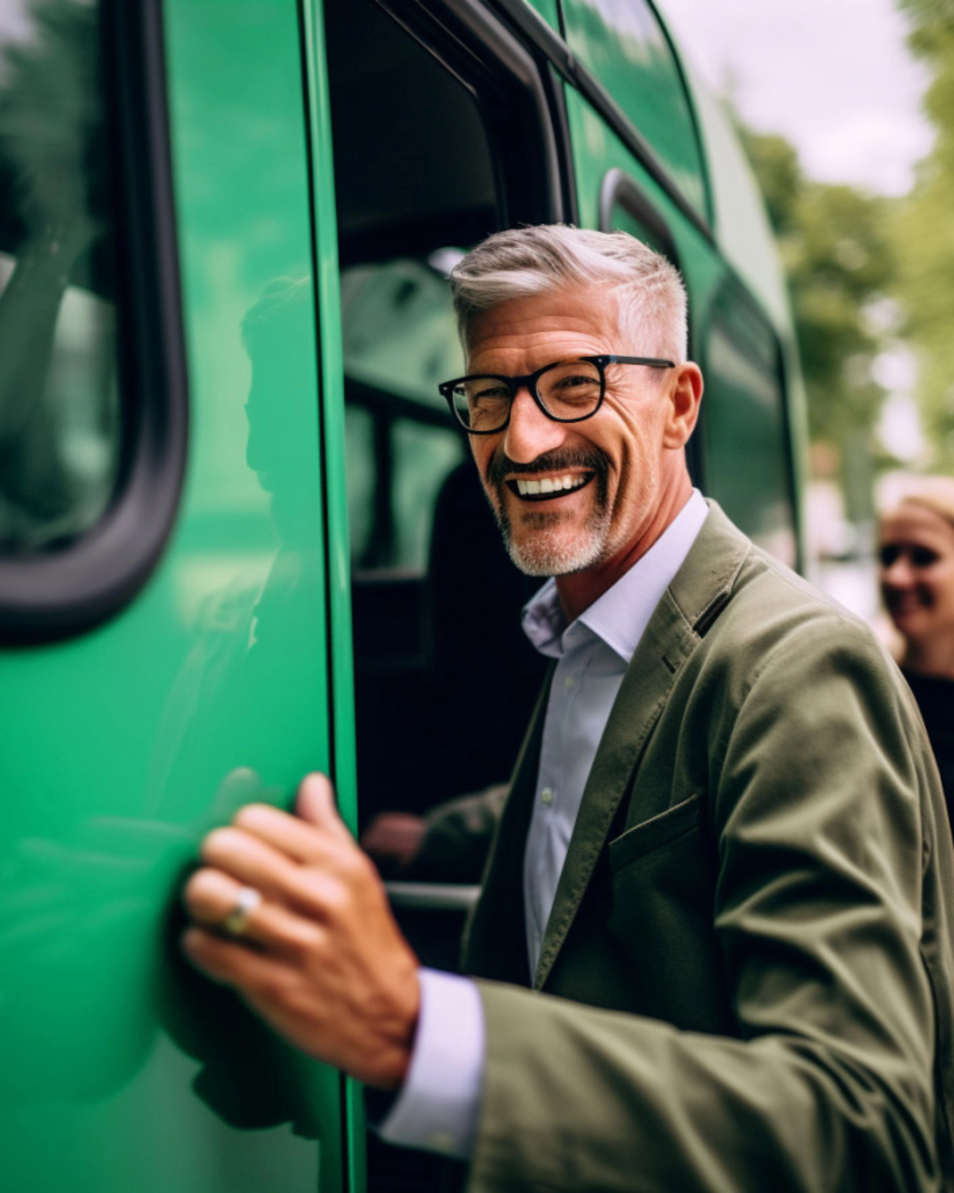 Lächelnder Mann mit Brille steigt in einen grünen Bus ein.