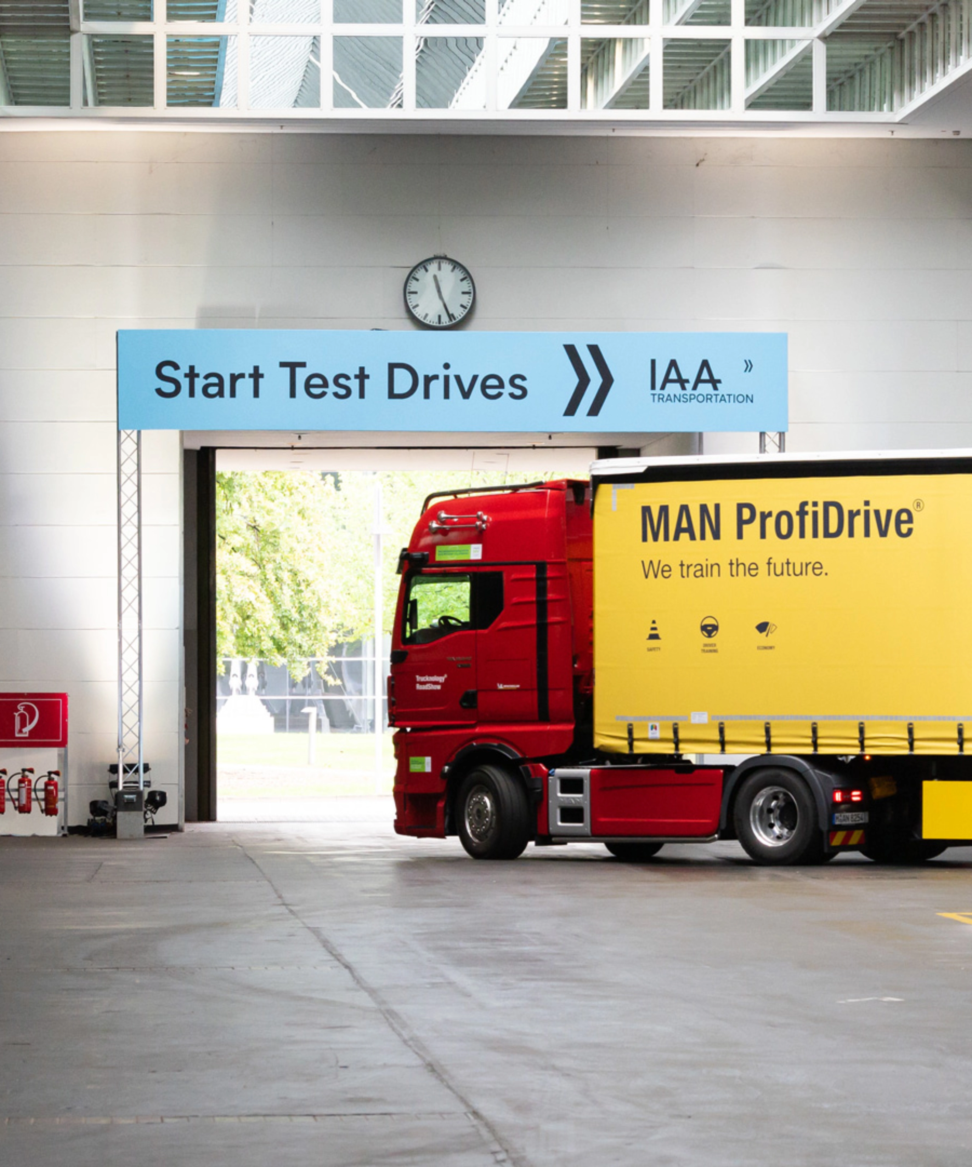 Truck with MAN ProfiDrive branding entering the IAA test‑drive start area inside a hall.