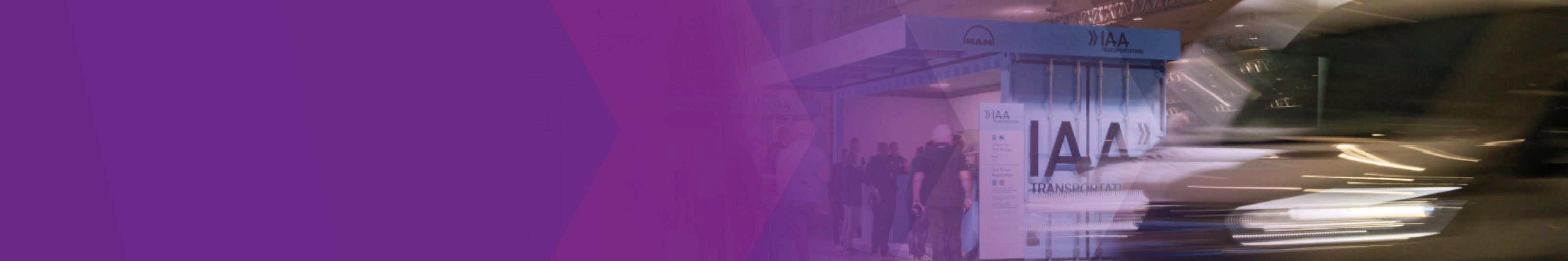 A blurred vehicle passes the IAA Transportation test drive check-in area, partly overlaid with purple graphics.