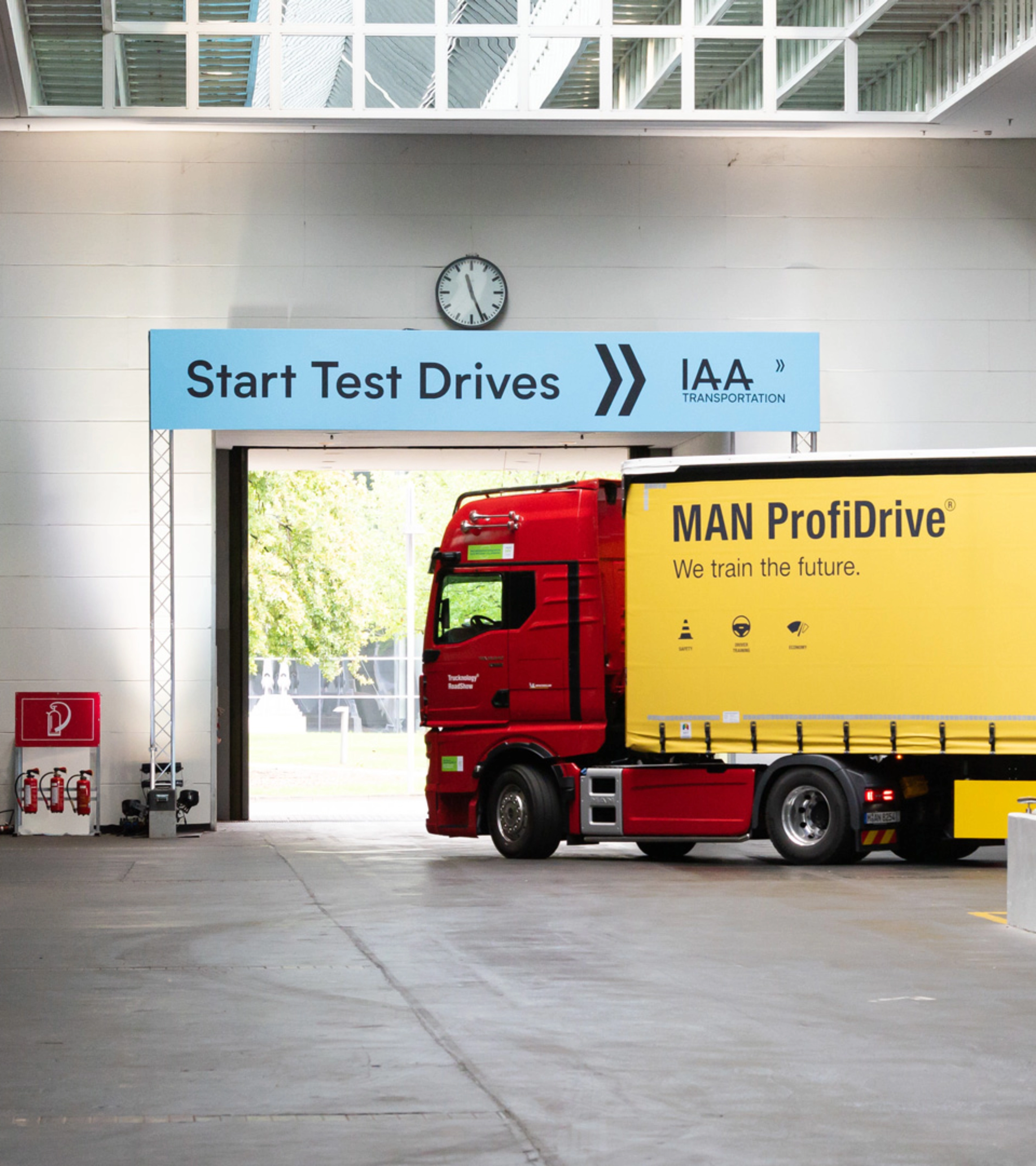 Truck with MAN ProfiDrive branding entering the IAA test‑drive start area inside a hall.