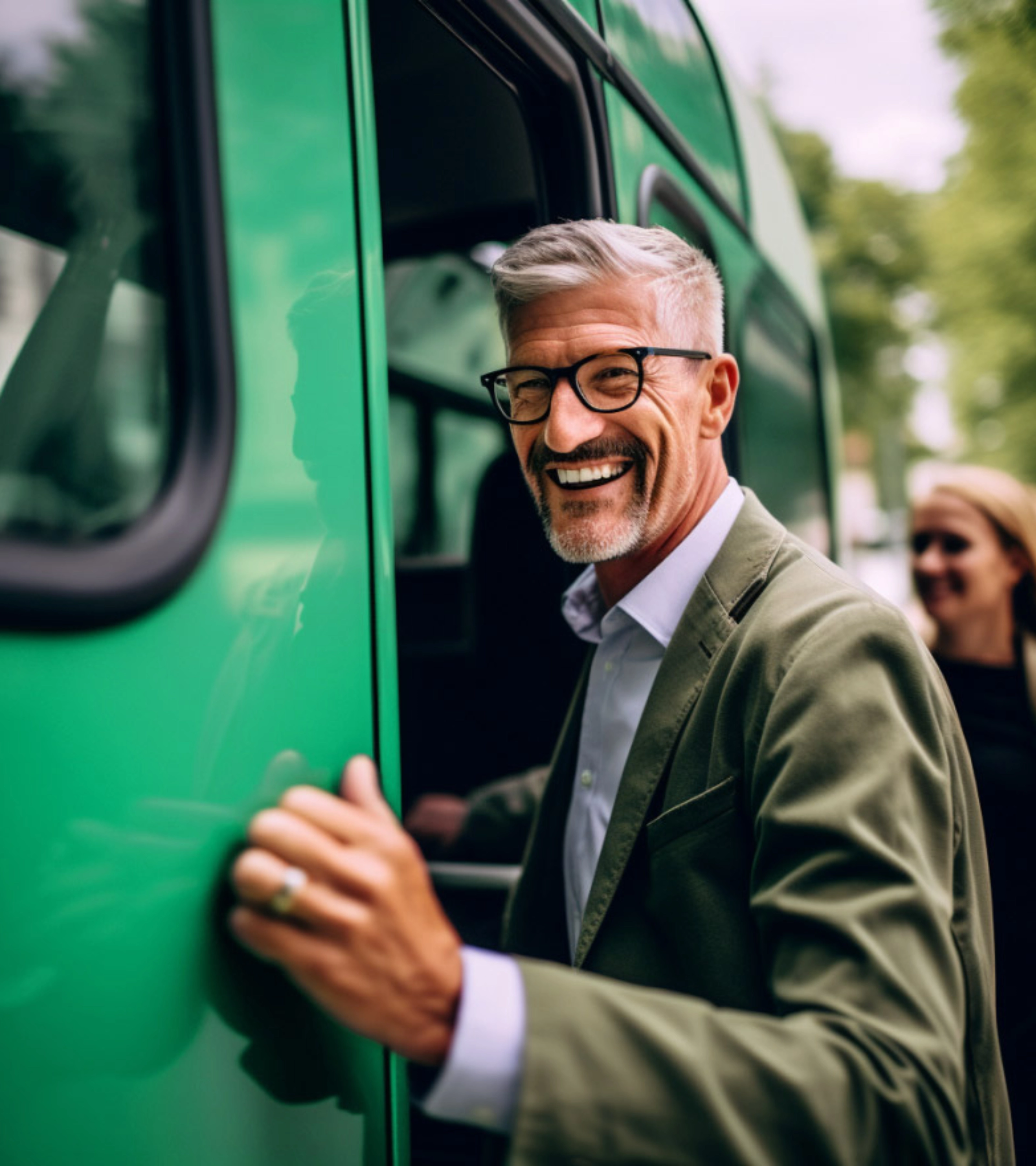 Lächelnder Mann mit Brille steigt in einen grünen Bus ein.