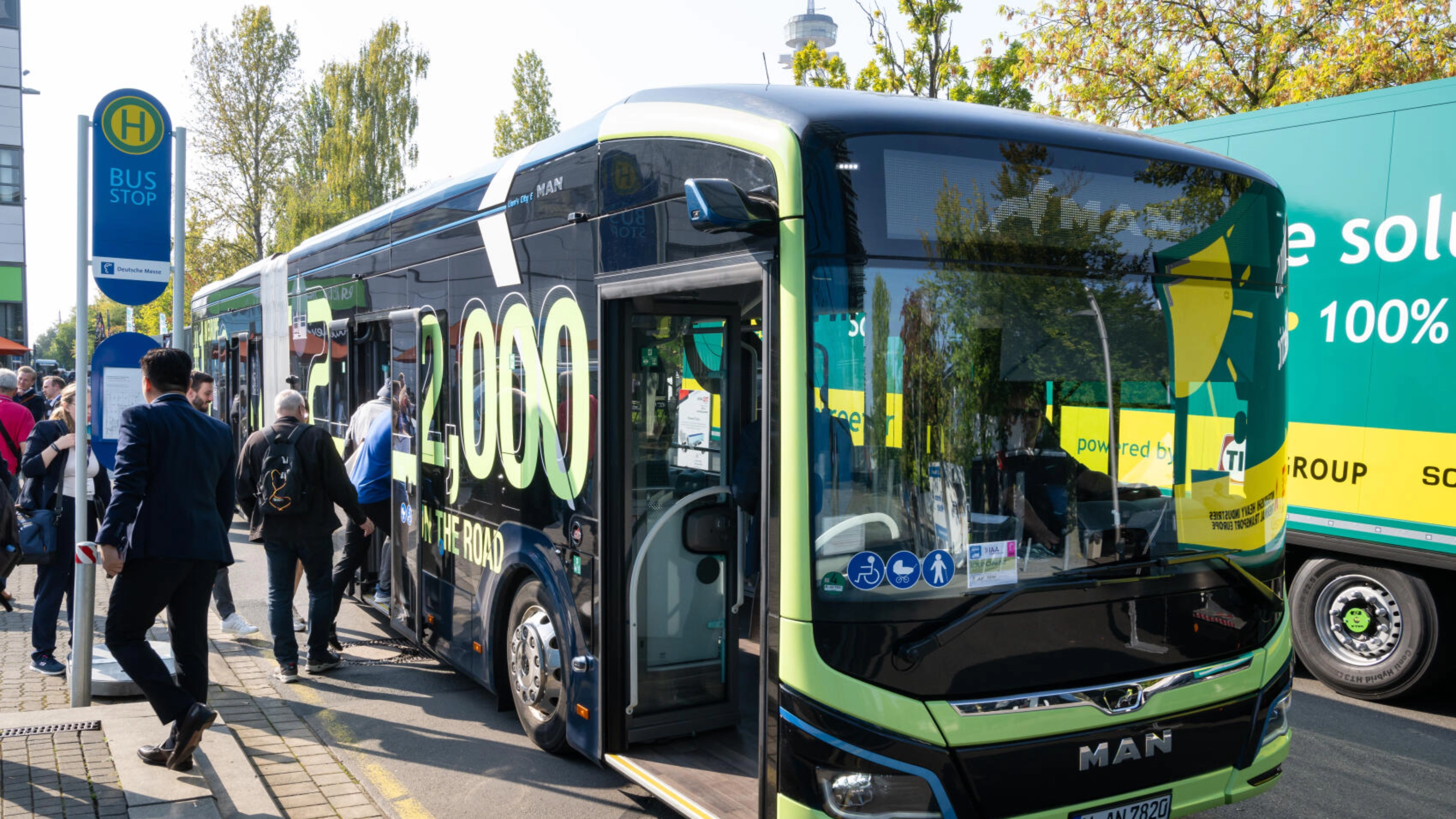People board a modern MAN shuttle bus at a bus stop during the IAA Transportation event.